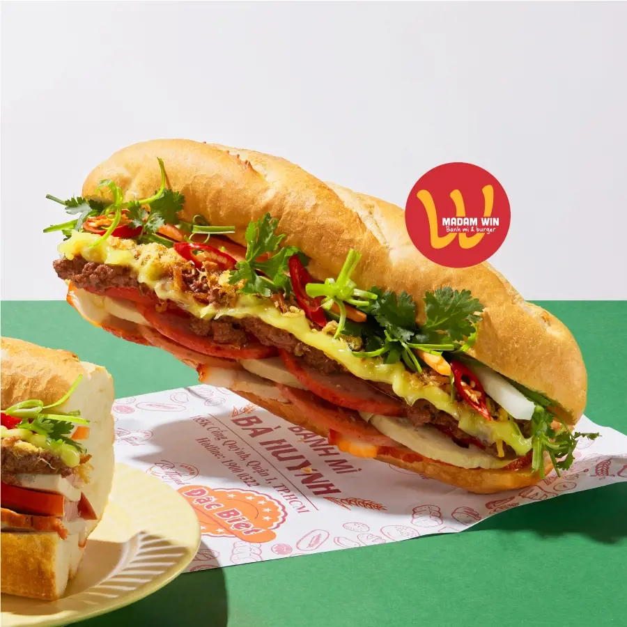 A fully stuffed Vietnamese bánh mì sandwich filled with savory meats, pâté, mayonnaise, fresh cilantro, and sliced red chilies.
