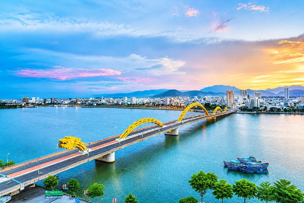 Cầu Rồng màu vàng uốn lượn bắc qua sông Hàn ở Đà Nẵng dưới ánh bầu trời hoàng hôn cam tím