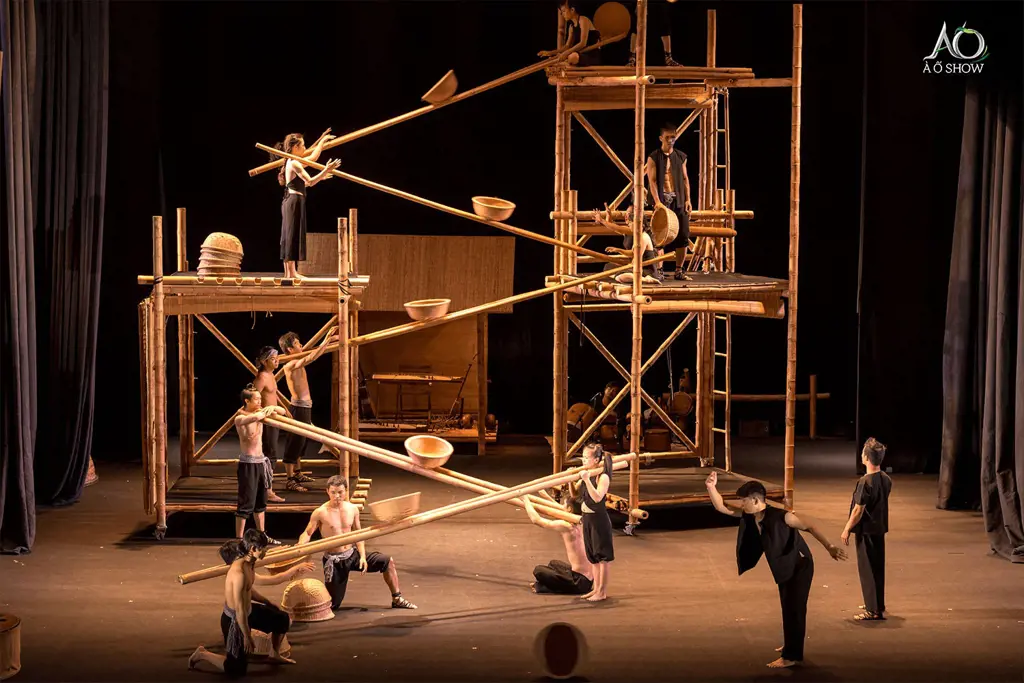 Acrobats and dancers perform on a theatrical stage using large bamboo scaffolding, long poles, and woven baskets.