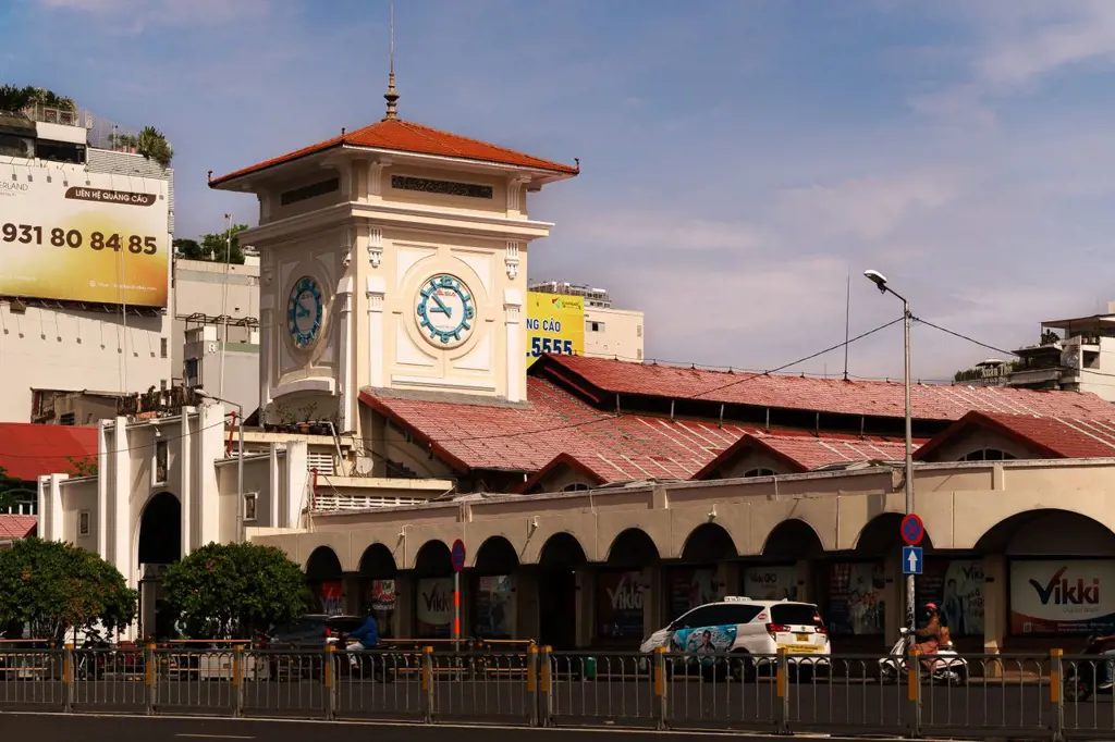 Exterior view of Ben Thanh Market featuring its prominent clock tower, terracotta roof, and street front in Ho Chi Minh City, Vietnam.